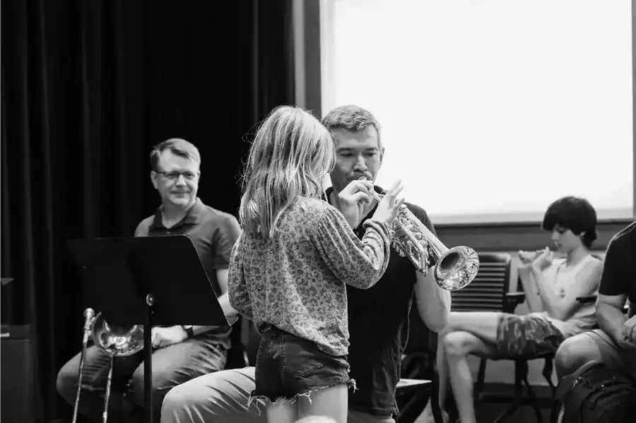 A young student learns trumpet from a New York Philharmonic Principal Brass musician